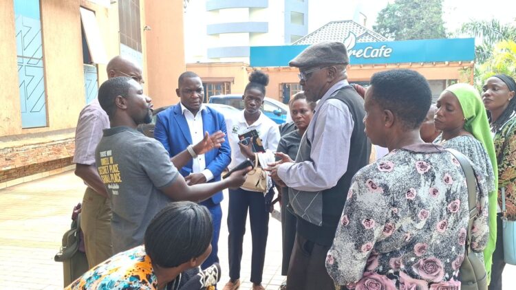 The Director Action for liberty and Economic Development (ALED), John Mugabi (3L) discusses with some of the previously affected traders outside the Civil Division of the High court in March, before a recent court judgement saw them regain their lost lockups in Kitooro Taxi Park. Photo /360 News Ug