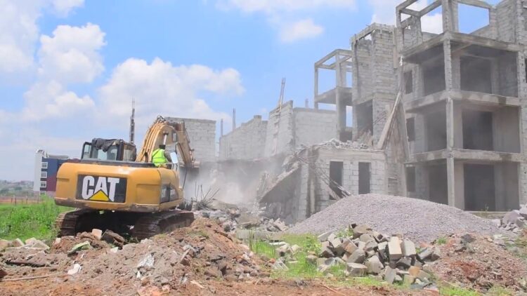 A grader razes down one of the multi million structures that had been constructed in Lumpewo wetland in Kajjansi Town Council, Wakiso District on Friday
